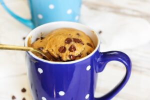 A Chocolate Chip Muffin in a blue mug with a spoon in it.