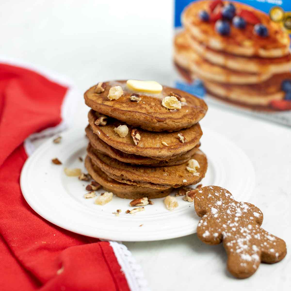 A stack of Gingerbread Pancakes topped with butter and chopped pecans.