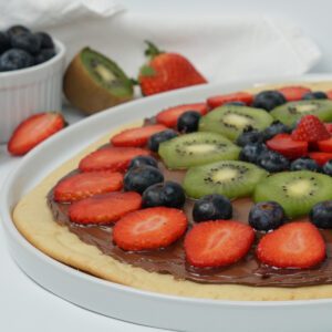 A Fruit Pizza Pancake with Nutella® topped with sliced strawberries and kiwi, and blueberries.