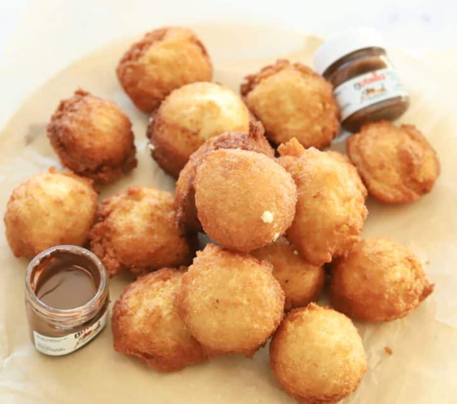 Several Zeppole Italian Donuts with two small Nutella® jars for dipping.