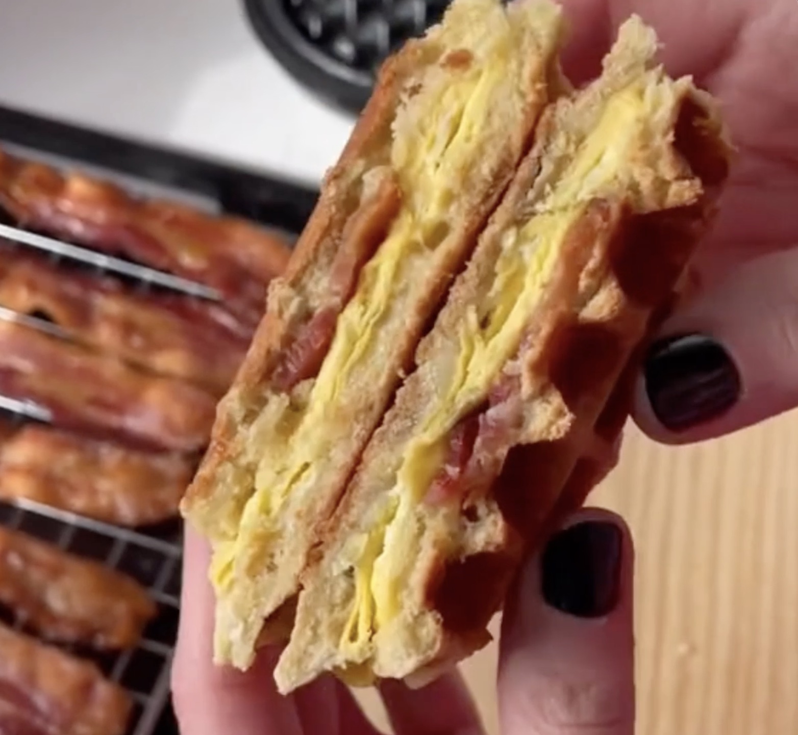 A Stuffed Waffle Breakfast Sandwich cut in half to display the layers of egg, bacon and cheese.