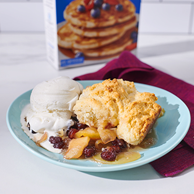 A serving of Apple Cranberry Cobbler paired with vanilla ice cream.
