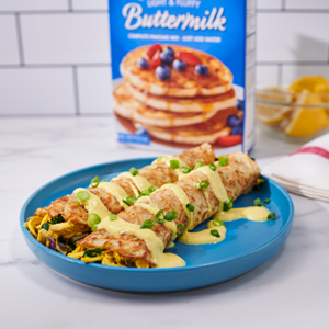 A plate of Curried Chicken and Spinach Crepes topped with a yogurt-based sauce and scallions.