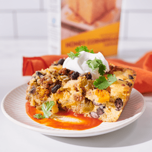 A plate of Taco Cornbread Casserole topped with sour cream and cilantro.