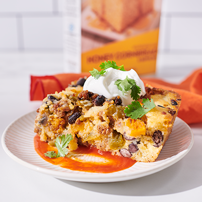 A plate of Taco Cornbread Casserole topped with sour cream and cilantro.