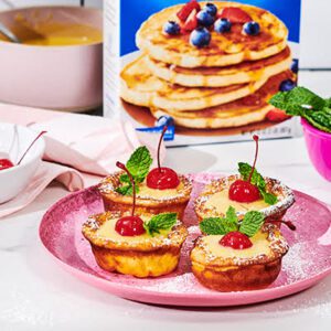 Four Mini Dutch Babies topped with a cherry and mint leaves on a plate.