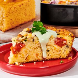 A plate of Vegetable Skillet Cornbread topped with cilantro avocado sour cream drizzle.