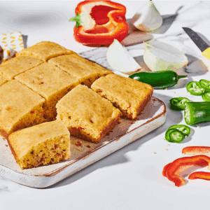 Pan of sweet and spicy cornbread surrounded by sliced peppers