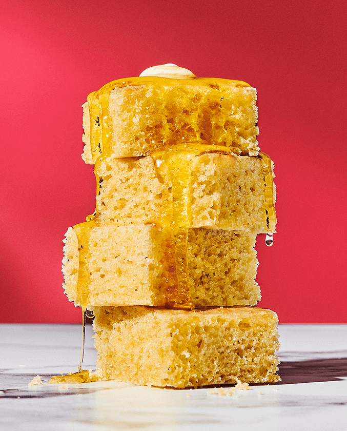 Four pieces of cornbread stacked with a honey drizzle