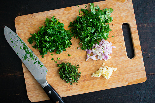 Various chopped herbs and onions on a bamboo cutting board